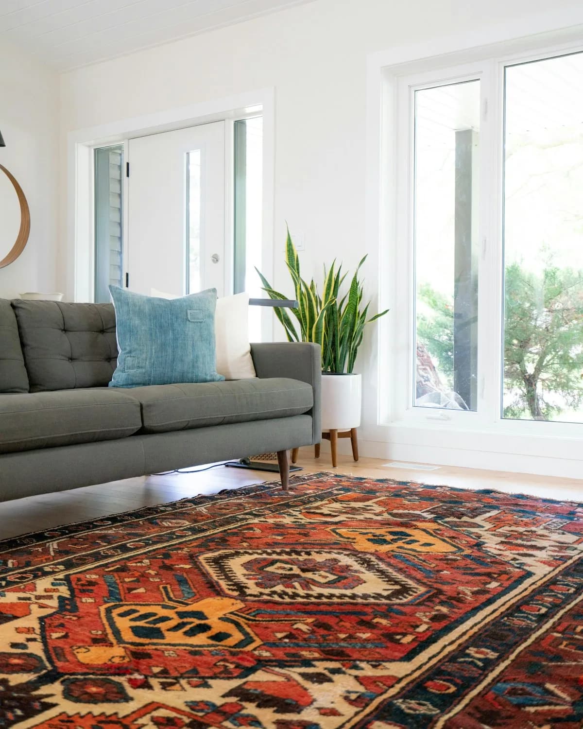 A hand-knotted wool rug on a deep madder ground, photographed in a room to show its scale against furniture